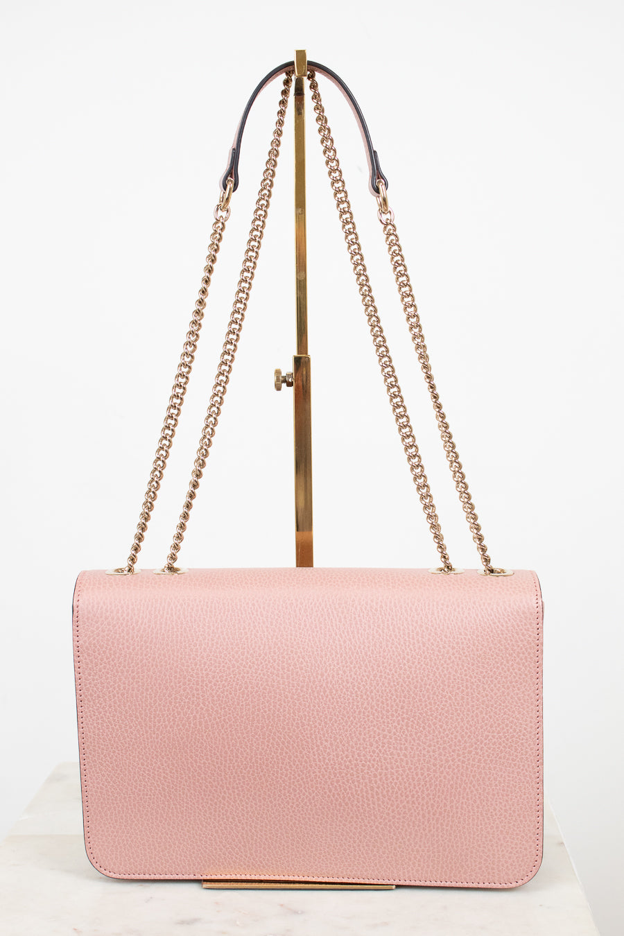 Pink handbag with gold chain strap on a white background