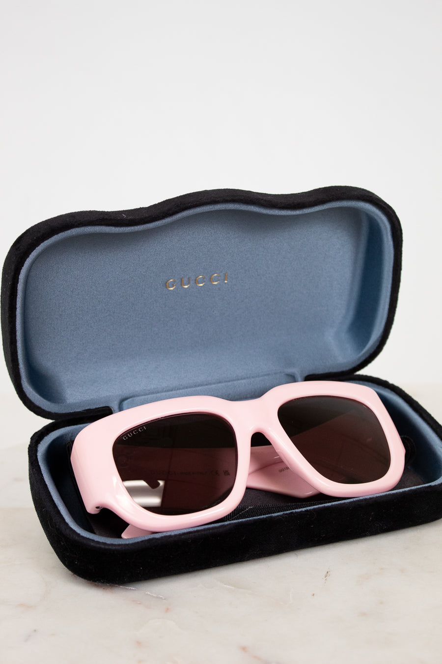 Pink sunglasses in a Gucci case on a light background