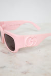 Pink sunglasses with a brand logo on a marble surface