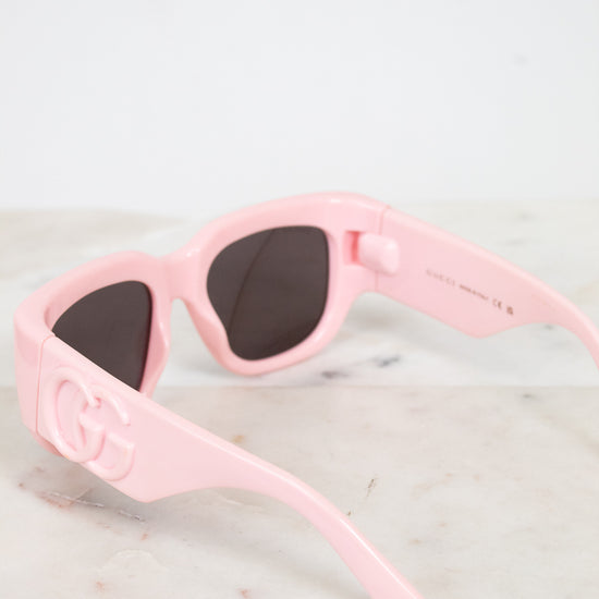 Pink sunglasses with dark lenses on a light marble surface