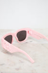 Pink sunglasses with dark lenses on a light marble surface