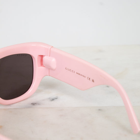 Pink sunglasses with dark lenses on a light marble surface