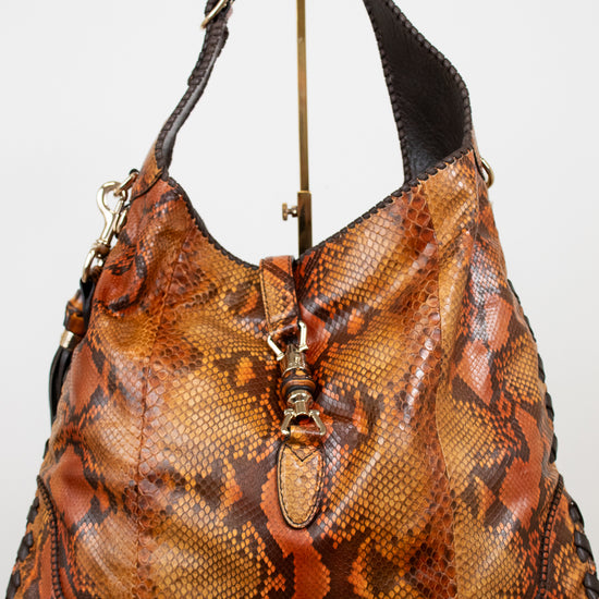 Brown snake skin patterned handbag on a white background