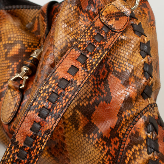 Brown snakeskin patterned handbag with a strap on a light background