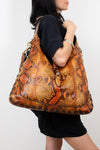 Person holding a large brown snake skin patterned handbag against a white background