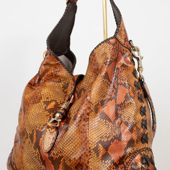 Brown snakeskin pattern handbag with black strap on a white background