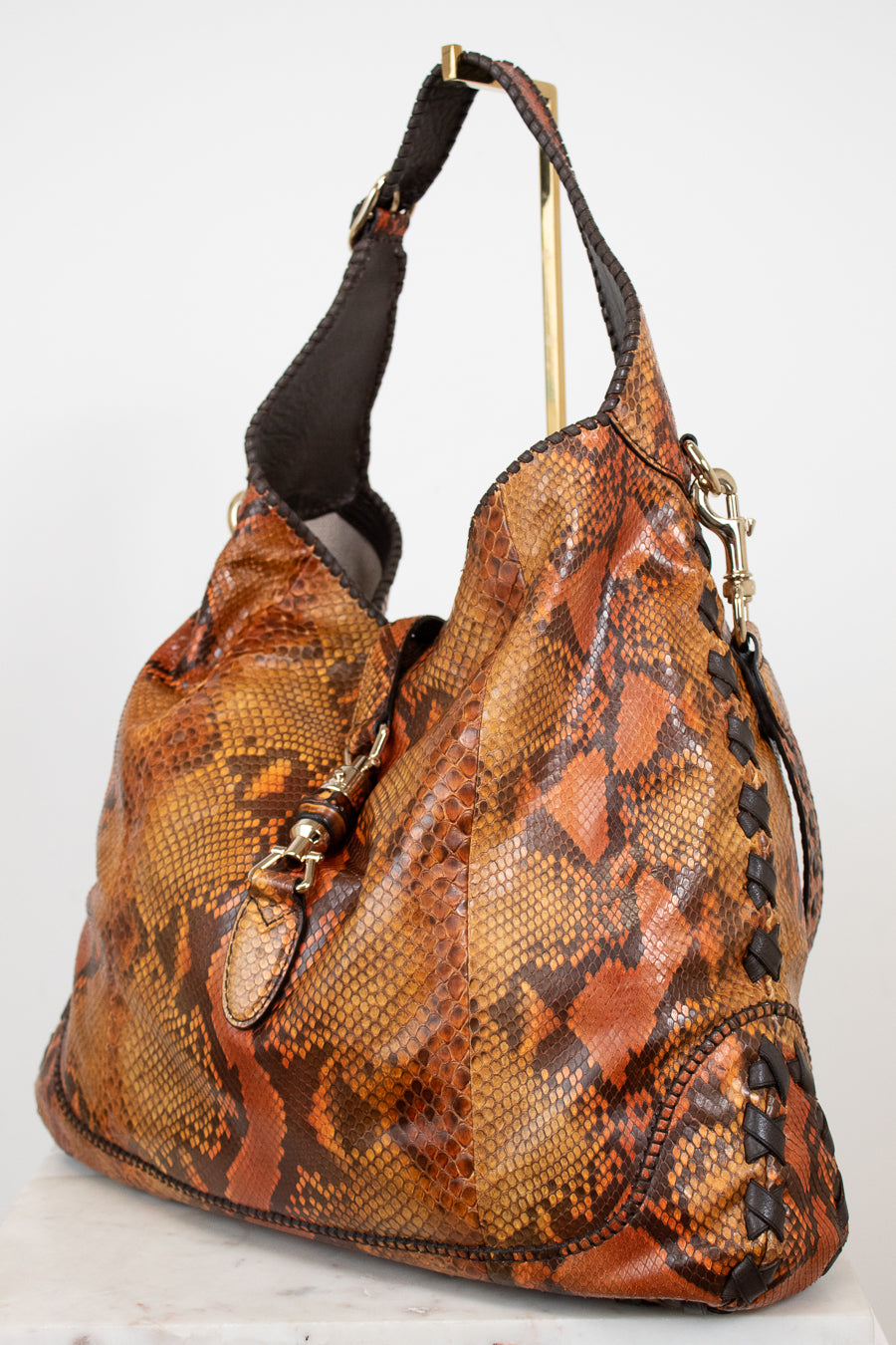 Brown snakeskin pattern handbag with black strap on a white background