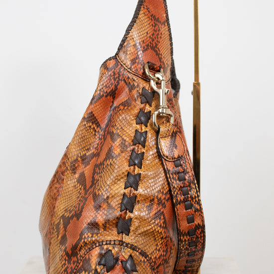 Brown snakeskin patterned handbag with gold accents on a white background