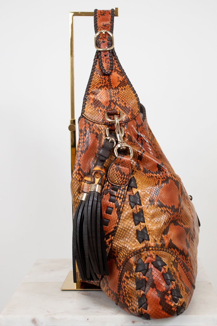 Brown leather sling bag with snake skin pattern on a white background