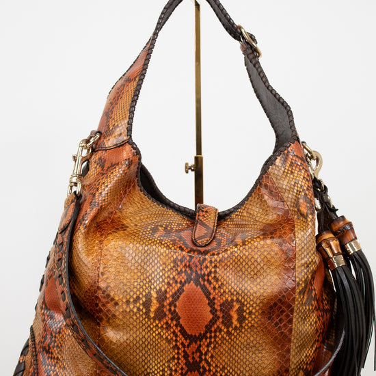 Brown snakeskin pattern handbag with gold accents on a white background