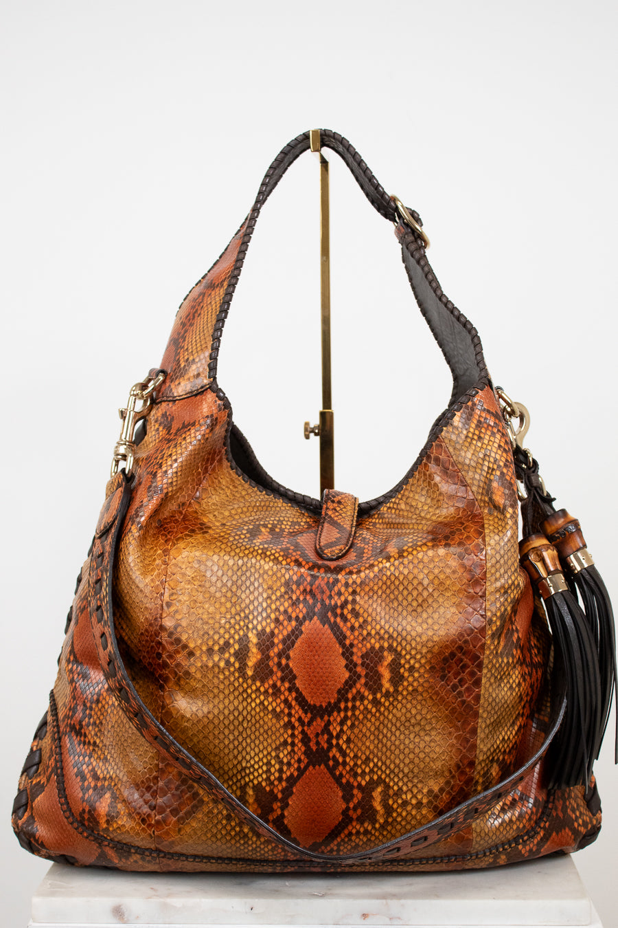 Brown snakeskin pattern handbag with gold accents on a white background