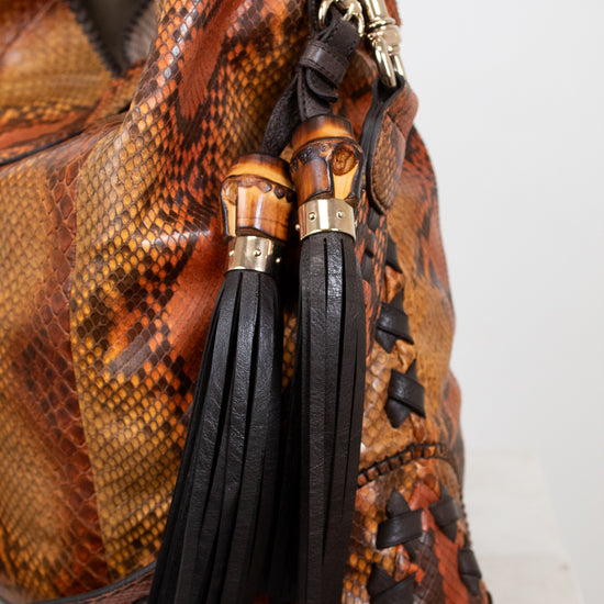 Brown textured handbag with black tassel on a white background