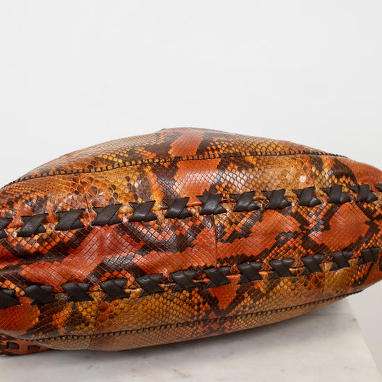 Snakeskin-patterned bag with black stitching on a white background