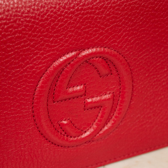 Red leather wallet with a "GG" Gucci brand logo on a light beige background