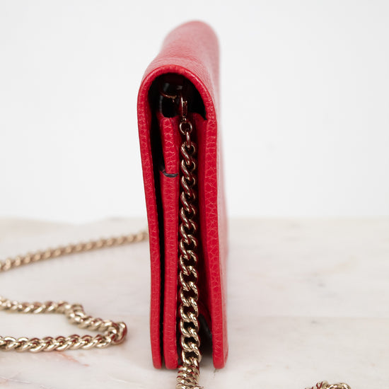 Red wallet with gold chain on a white marble surface