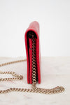 Red wallet with gold chain on a white marble surface