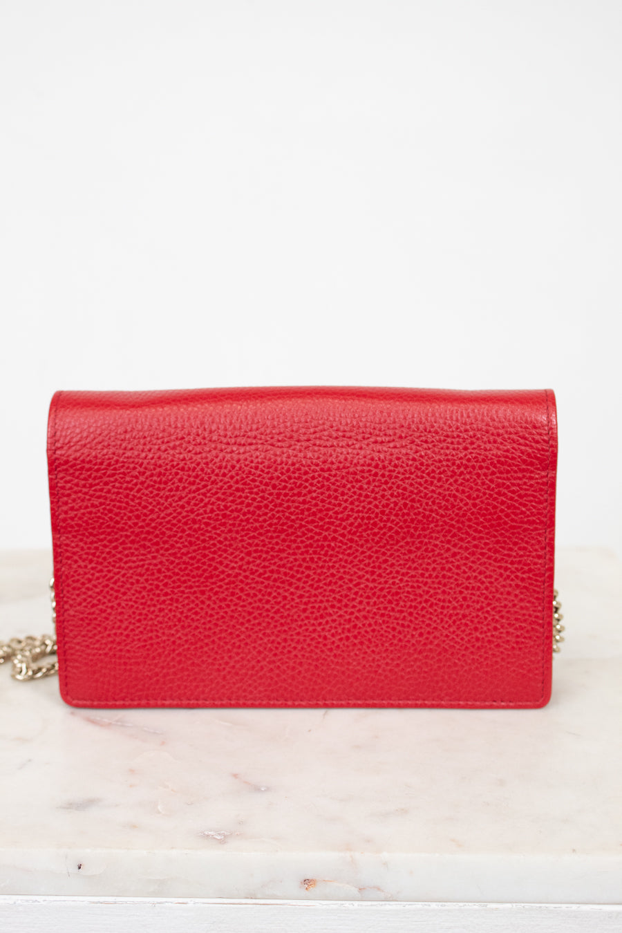 Red handbag on a white marble surface