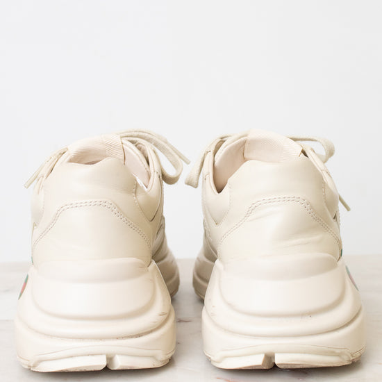A pair of off-white Gucci sneakers shown from the back sitting on a light marble and against a light background.