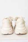 A pair of off-white Gucci sneakers shown from the back sitting on a light marble and against a light background.
