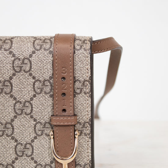 Gucci handbag with brown strap and logo pattern on a white background