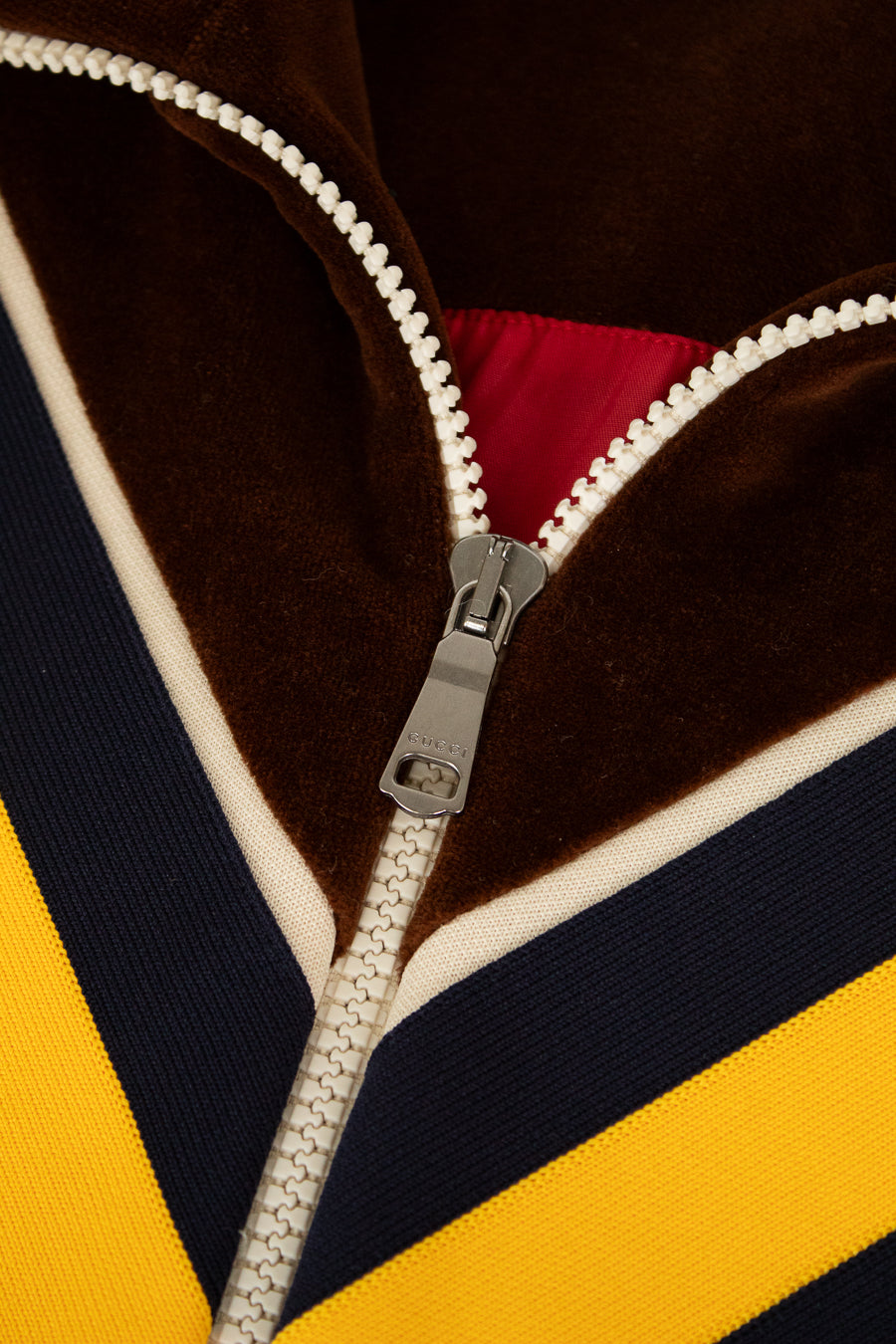 Close-up of a zipper on a multicolored jacket with brown, yellow, and black stripes.