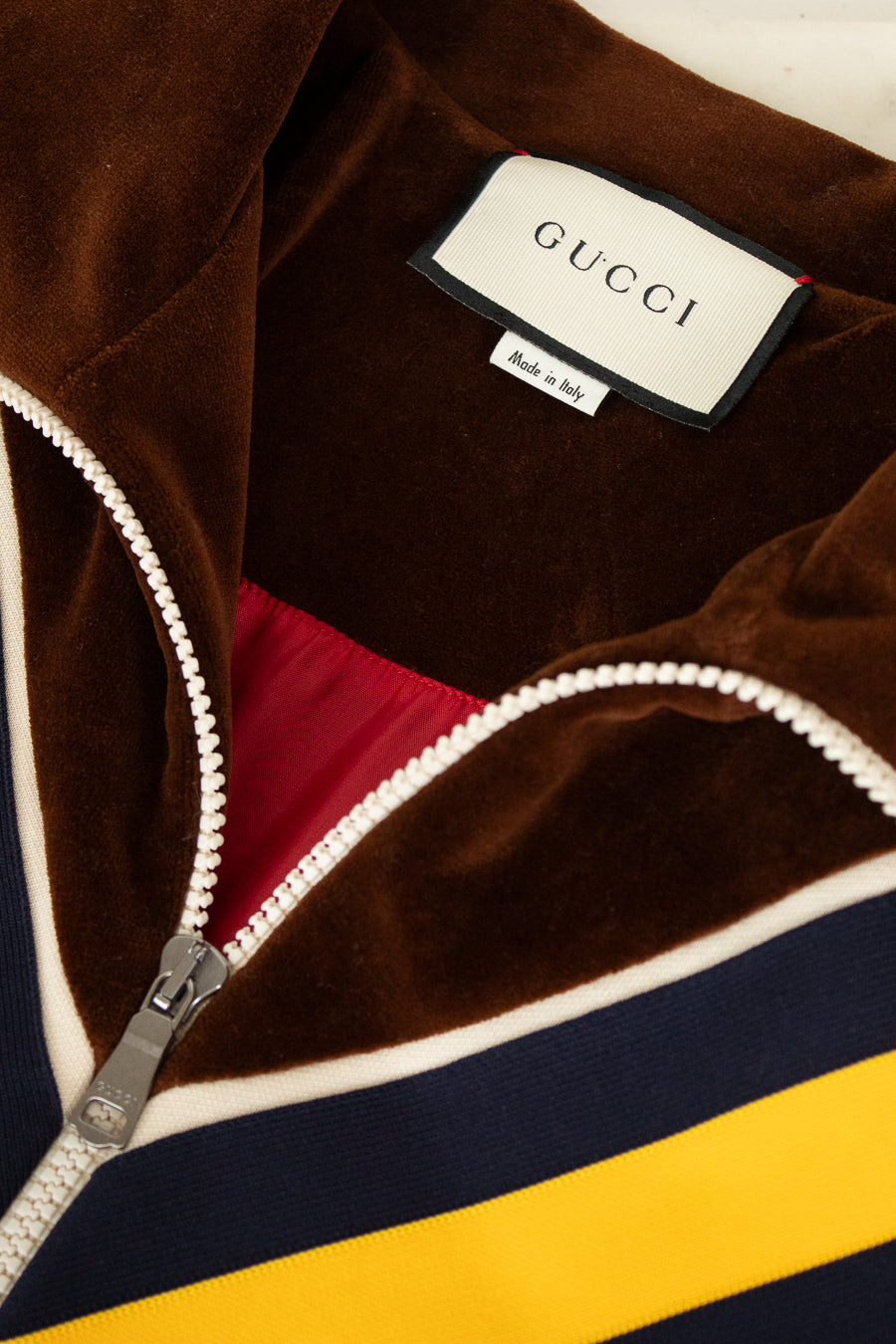 Close-up of a Gucci label on a multicolored jacket with a zipper.