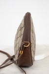 A vintage Gucci monogram canvas pouch with brown leather trim and gold-tone hardware, shown from a side profile view on a light marble surface.