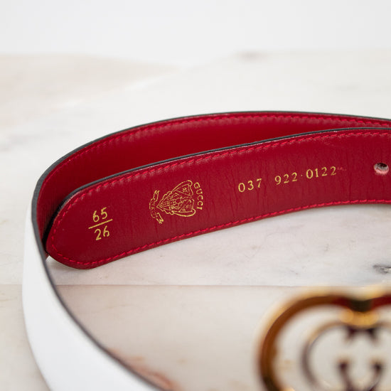 White and red belt with gold and silver logo and gold text interior on a marble surface