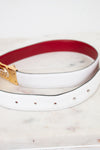 White and red reversible belt with a gold and silver buckle on a marble surface
