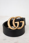 Black belt with gold double G buckle on a light marble background
