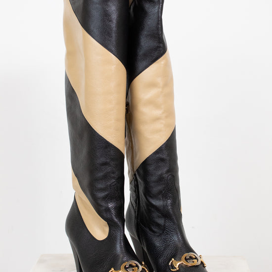 Black and beige asymmetrical leather stripes of boot with two-tone 'GG' toe detail standing against a white background
