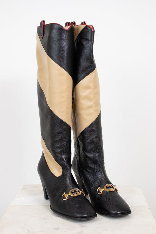 Black and beige asymmetrical leather stripes of boot with two-tone 'GG' toe detail standing against a white background