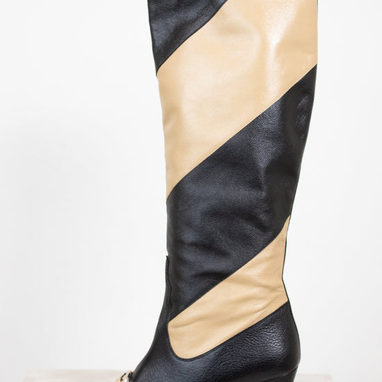 Side profile of black and beige asymmetrical leather stripes of boot with two-tone 'GG' toe detail standing against a white background