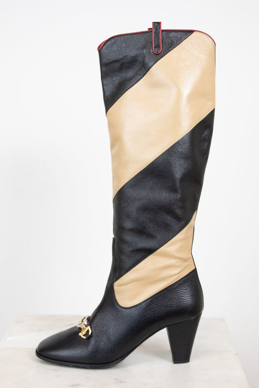 Side profile of black and beige asymmetrical leather stripes of boot with two-tone 'GG' toe detail standing against a white background