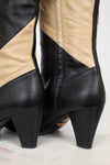 Close up of heel of black and beige striped leather boot standing on a plain marble surface