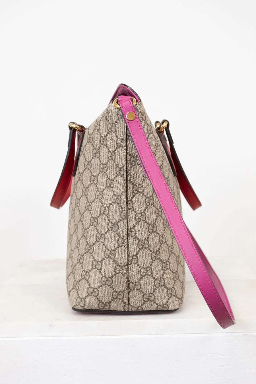 Beige handbag with pink strap on a white background