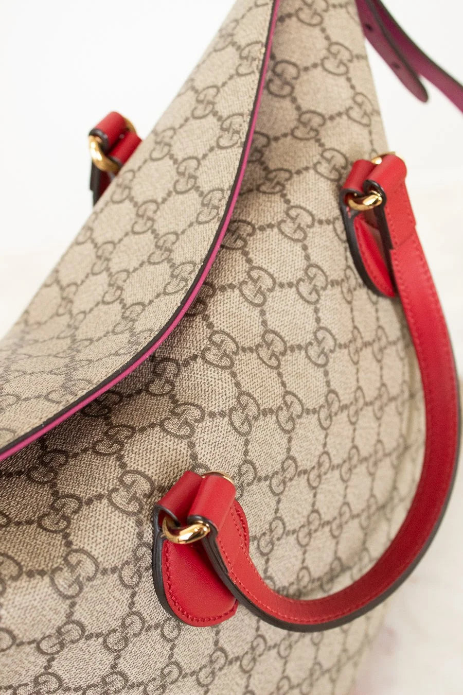 Beige handbag with red handles and trim on a light background