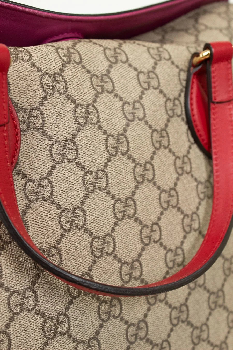 Close-up of a Gucci handbag with red accents and monogram pattern.