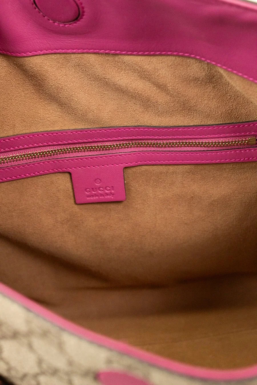 Close-up of a brown interior with pink zipper and visible Gucci logo.