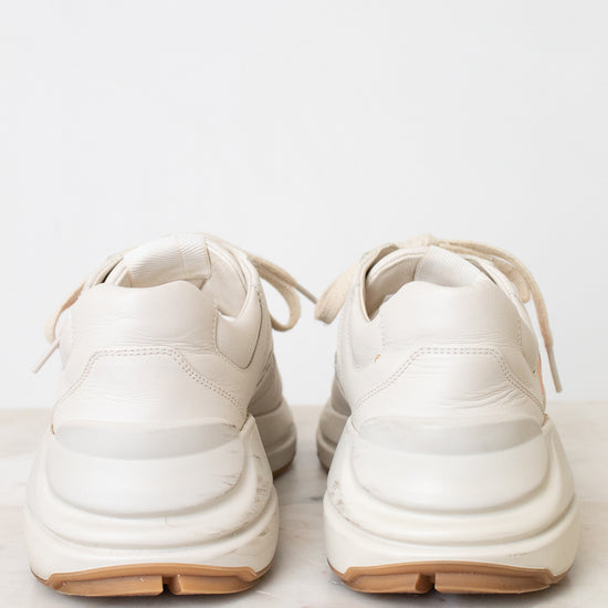 A white leather sneaker photographed from the back set against a plain white background.