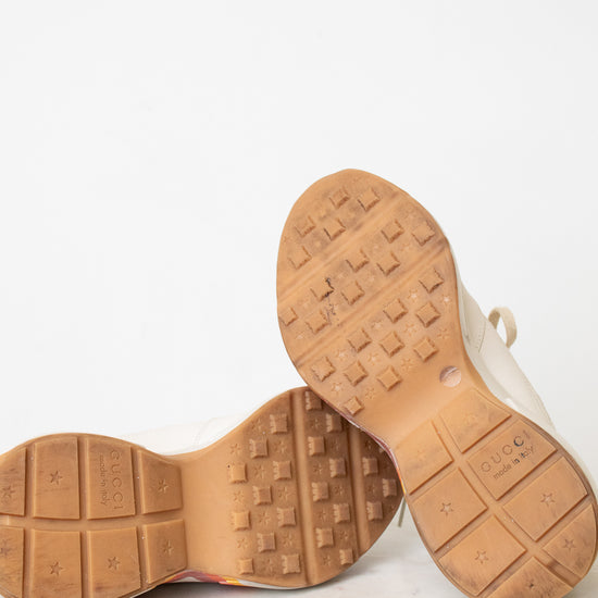 Close-up of the tan rubber soles of a pair of shoes, showing tread patterns and size markings, photographed against a plain white background.