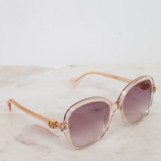 Rose gold sunglasses with pink gradient lenses on a marble surface