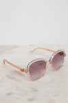 Rose gold sunglasses with pink gradient lenses on a marble surface