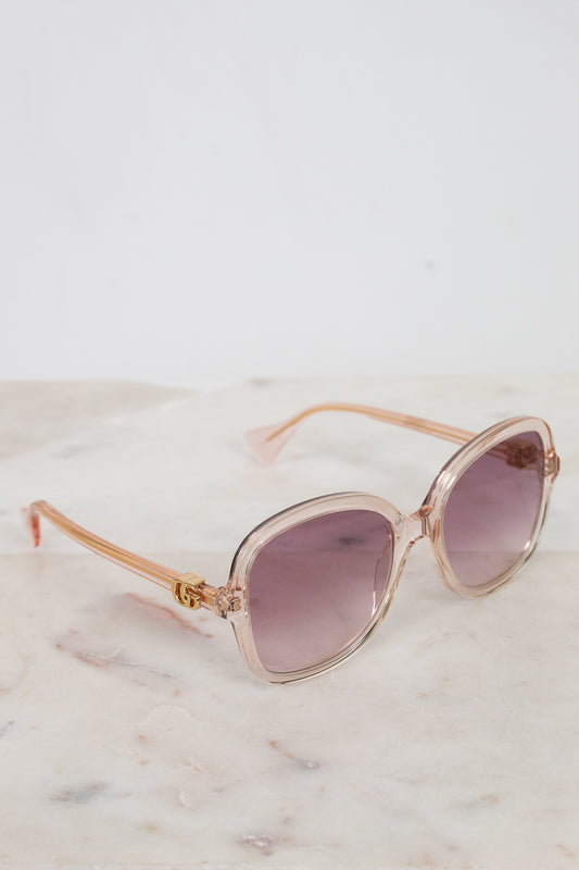 Rose gold sunglasses with pink gradient lenses on a marble surface