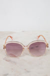 Sunglasses with a pink tinted frame and purple lenses on a marble surface