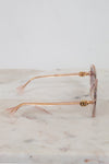 Gold-detail framed sunglasses with pink frames and lenses on a marble surface
