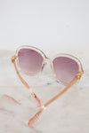 Sunglasses with pink and gold frame and pink lenses on a marble surface
