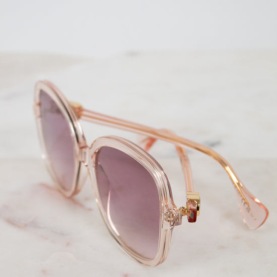 Pink and gold sunglasses with pink gradient lenses on a marble surface