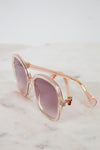 Pink and gold sunglasses with pink gradient lenses on a marble surface