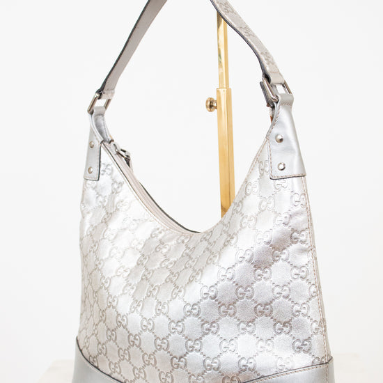 Silver handbag with Gucci pattern on a white background